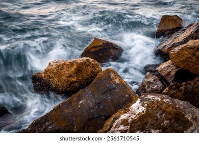 Close-up of Stones Rocks on the Coast with the Sea Water with Silky Effect at Sunset Light. Slow Shutter Speed Photo - Powered by Shutterstock