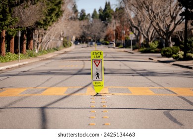 Close-up of a "Stop forto  pedestrians within crosswalk" sign on a street on a sunny day, blurred trees and urban street in the background. Pedestrian safety and car driving rules. walk.  - Powered by Shutterstock