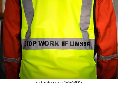 Close-up at "Stop work if unsafe" sign label on back of reflective vest which is wear by a lifting signaler worker. Safety conception photo for heavy industry operation.
