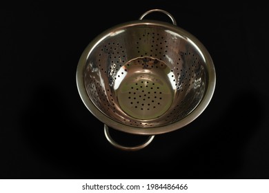 A closeup of a strainer on a black background