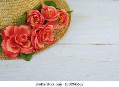 Closeup of a straw bonnet decorated with multiple silk roses on a white washed wooden background with copy space. Good for spring, summer, wedding or Kentucky Derby.