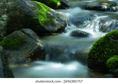 A closeup of a stream with a long exposure effect with  mossy,green stones around