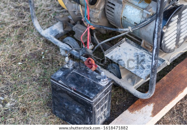 close-up. Street lighting. A gasoline-powered
generator that produces current. A car battery is connected for
charging. Backup or emergency power source. The generator is not
new.