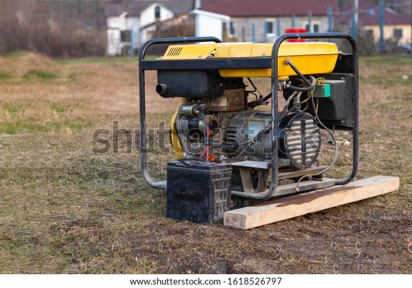 close-up. Street lighting. A gasoline-powered\
generator that produces current. A car battery is connected for\
charging. Backup or emergency power source. The generator is not\
new.