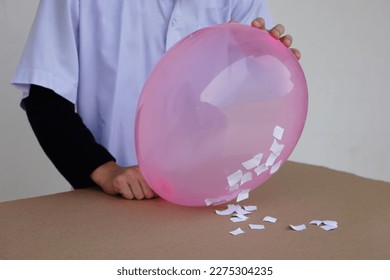Closeup student do science experiment about static electricty from pink balloon and pieces of paper. Concept, Science project work activity. Learning by doing. Education.                         