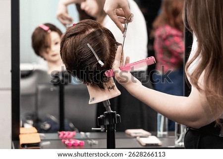 Close-up of student hands using scissors to cut synthetic hair on mannequin in beauty training session