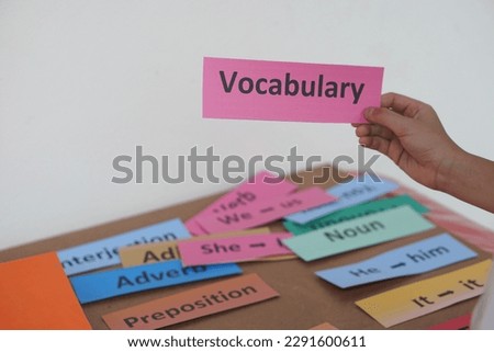 Closeup student's hand hold English vocabulary word card. Concept, education, learning, studying language. Education. Reading and memorizing strategy of learning process for kid. Practice make perfect