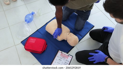 Closeup Of Students Practicing CPR Chest Compression On Teen Dummy.