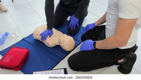 Closeup Of Students Practicing CPR Chest Compression On Teen Dummy.