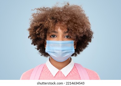 Close-up Studio Portrait Of African American School Girl Or College Student With Curly Afro Hair Wearing Medical Mask, Isolated On Blue Background