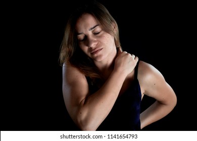 Closeup studio portrait of a beautiful young woman with pain in her neck and back, isolated on black background. Cervical arthritis, diseases of the musculoskeletal system concept.