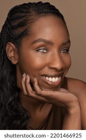 Close-up studio portrait of a fit Black woman with long braided hair in her 30's with visual impairment on a neutral background, hand under chin Stock Photo