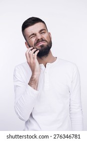 Close-up Studio Portrait Of A Grimacing Thinking Man Irritable Itchy His Beard. Isolated On A Light Background.