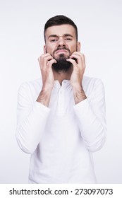 Close-up Studio Portrait Of A Man Irritable Itchy His Beard And Wants To Shave It. Isolated On A Light Background.