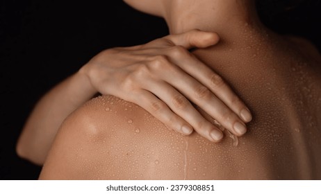 Closeup studio shot of beautiful woman body, touching skin with water drops on the shoulder back area after bathing.