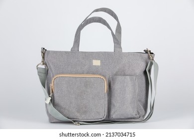 Closeup studio shot of gray color multifunction multipurpose utility zipper newborn baby toddler mommy handbag with milk bottle pocket handle and long durable adjustable strap on white background.