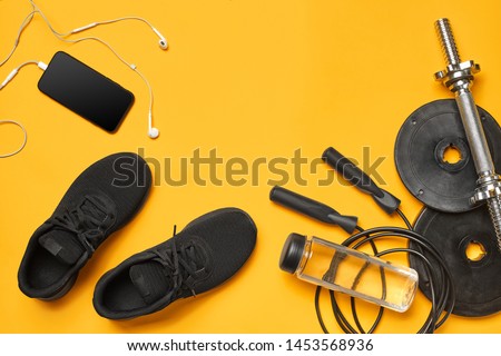 Close-up studio shot of a gym accessories on a yellow background. Top view, flat lay.