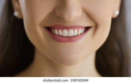 Closeup studio shot of happy young woman's smile with perfect white even healthy teeth. Lower part of dentist's customer's face. Dental care, oral health, whitening results, hygiene and beauty concept - Shutterstock ID 1987453949