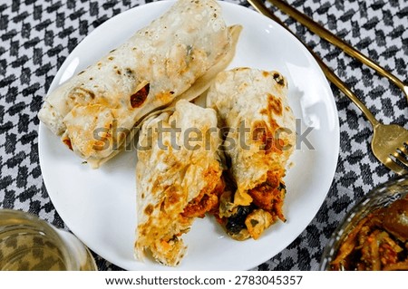 Closeup stuffed flatbread wraps filled with spiced chicken and fresh vegetables served on elegant plate. Authentic halal street food and Ramadan dining concept with rich flavors.