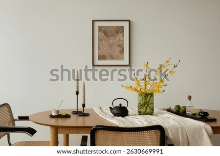 Close-up of a styled dining table with yellow forsythia flowers, spiral candles, limes, and a black teapot. Elegant spring tabletop arrangement in natural tones.