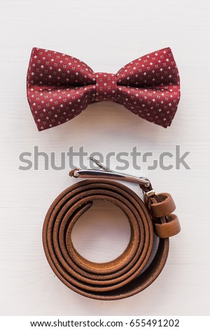 Closeup of stylish brown male accessory isolated on white wooden background. Vertical top view flat lay photography.