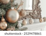 Close-up of stylish Christmas tree decorations, including gold and silver ornaments, against the backdrop of an elegant mirror in a white room.