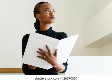 Close-up Of Successful African Or Black American Business Woman Holding Big White File And Thinking