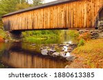 Closeup of Sugar River flowing beneath historic Corbin wooden bridge in Newport, New Hampshire, on a rainy fall day. 