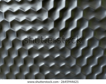 Close-up of a suitcase surface with raised hexagonal texture. The material appears metallic or hard plastic with light reflections, giving it a modern and futuristic look