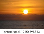 Close-up of the sun rising through the clouds at sunrise on the beaches of Mojacar. Holiday and beach sunrises.