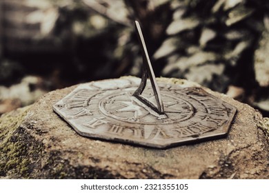 A closeup of a sunlit sundial set in a stone blurred background