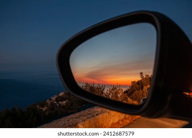 Closeup of a sunset in nature seen from the side mirror of stopped car. Car trip concept - Powered by Shutterstock