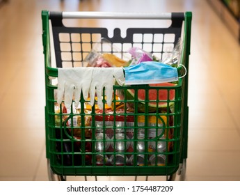 Close-up Of A Supermarket Trolley With Protective Gloves And Mask Resting On The Handlebar, Filled With Food, No Person, Bright Light In Background.