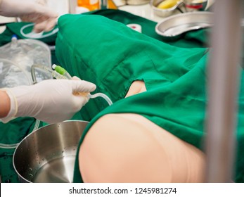 Closeup of a surgical physician practicing urinary catheter insertion on a plastic training model. Emergency healthcare and education concept.