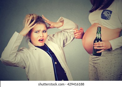 Closeup surprised doctor and pregnant woman with bottle of beer and cigarette in hand isolated on gray wall background 