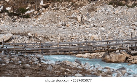 Close-up of a suspended wooden footbridge over a rocky bed of a mountain river.                      - Powered by Shutterstock