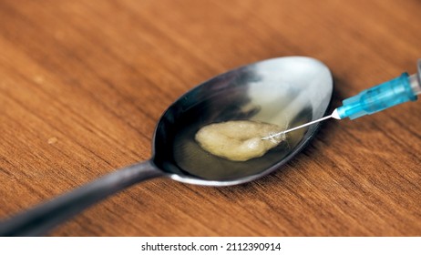 Close-up Of Syringe Needle Extracting Heroin From A Spoon After Cooking Using The Filter. Drug Abuse And Opiate Addiction.