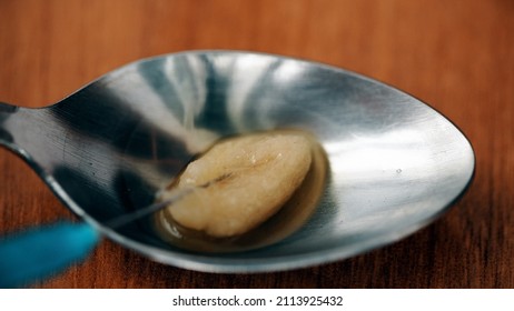 Close-up Of Syringe Needle Extracting Heroin From A Spoon After Cooking Using The Filter. Drug Abuse And Opiate Addiction.