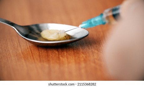 Close-up Of Syringe Needle Extracting Heroin From A Spoon After Cooking Using The Filter. Drug Abuse And Opiate Addiction.