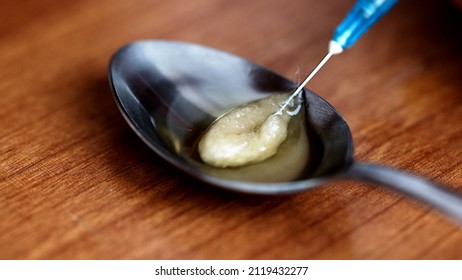 Close-up Of Syringe Needle Extracting Heroin From A Spoon After Cooking Using The Filter. Drug Abuse And Opiate Addiction.