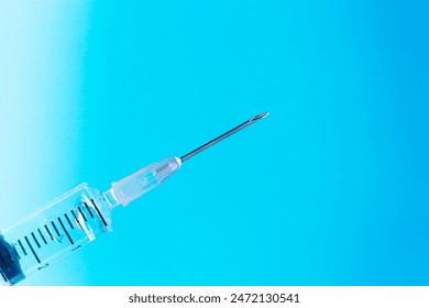 Close-up of syringe needle on isolated blue background,A doctor's hand in blue gloves picks up liquid from a vial into a syringe close-up on a blue background. Vaccine against covid-19. Insulin shot.  - Powered by Shutterstock