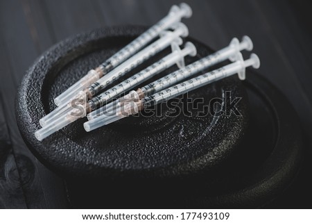 Close-up of syringes atop of cast-iron weight disks