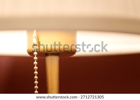 Close-up of a Table Lamp Pull Chain Detail Showing Golden Beaded Chain and Soft Lampshade