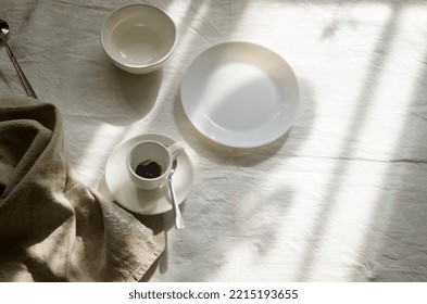 Close-up of Table setting. Top view of empty white plate with cutlery and linen napkin on white tableclosh. Cozy calm meal in the morning in the sunshine. - Powered by Shutterstock