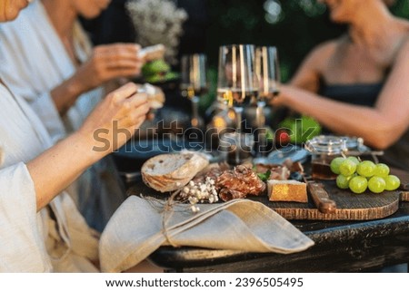 Close-up of a table with wine glasses, bread, and grapes, friends dining in the background