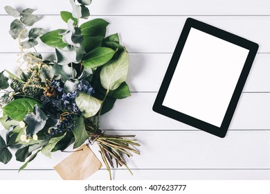 Closeup tablet with a empty blank screen monitor with a bouquet of flowers on white table background  with natural wood planks top view, touch pad with space for publicity information or text - Powered by Shutterstock