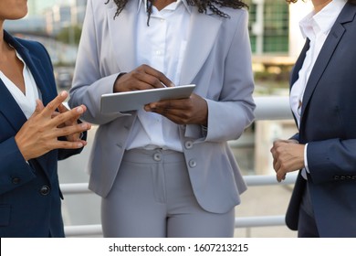 Closeup of tablet in female hands. Businesswomen standing outside and using digital device together. Teamwork or communication concept