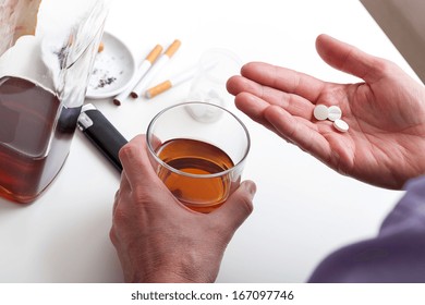 A closeup of taking pills washed down with whisky