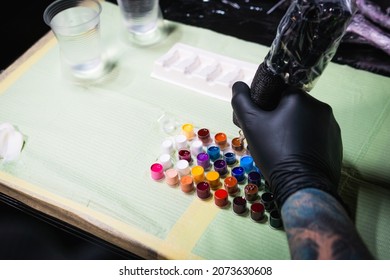 Close-up Of Tattoo Artist Work Place Parts And Paint, Machines And Other Equipment. Professional Tattooist Working In Studio