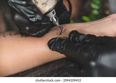 Closeup Of A Tattoo Machine With A Round Liner Cartridge Operated By A Professional Tattoo Artist. Tattooing Cursive Letters.